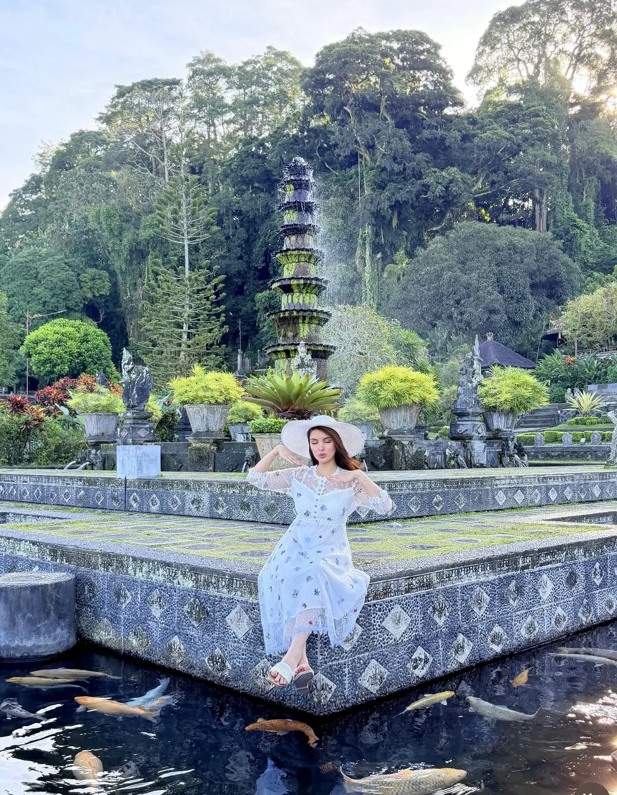 A visitor seated beside a koi pond with a multi-tiered tower behind