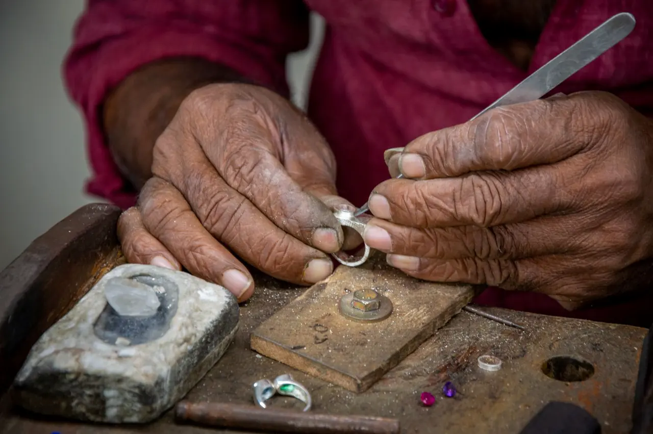 A craftsman shaping a silver ring by hand at a workshop bench (illustrative photo)